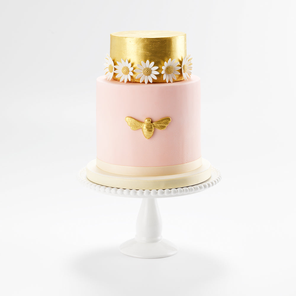 Decorated with a handmade golden sugar bee and white sugar daisies, this two tier celebration cake, suitable for any ocasion, serves 40 portions, and is ready to be delivered in 2 days